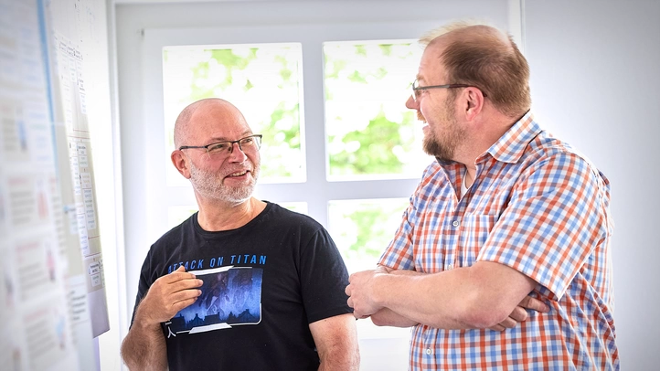 Two men are talking at a flipchart.