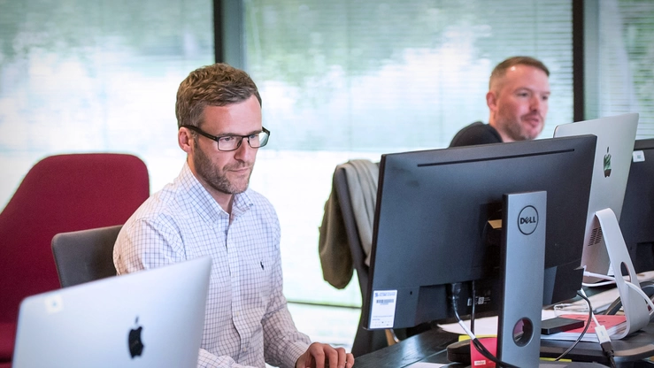 Zwei Personen arbeiten im Büro am PC.