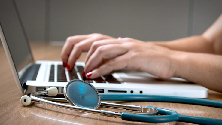 Eine Medizinalperson tippt auf einem Laptop