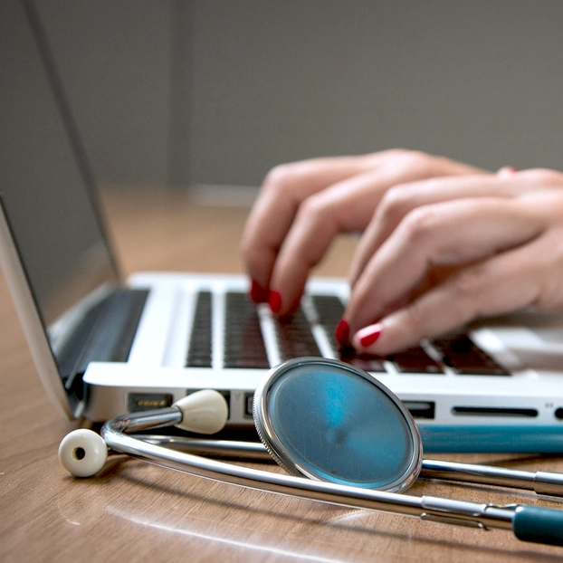 Eine Medizinalperson tippt auf einem Laptop