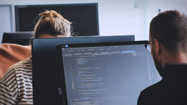 Deux personnes travaillent sur un PC dans un bureau.